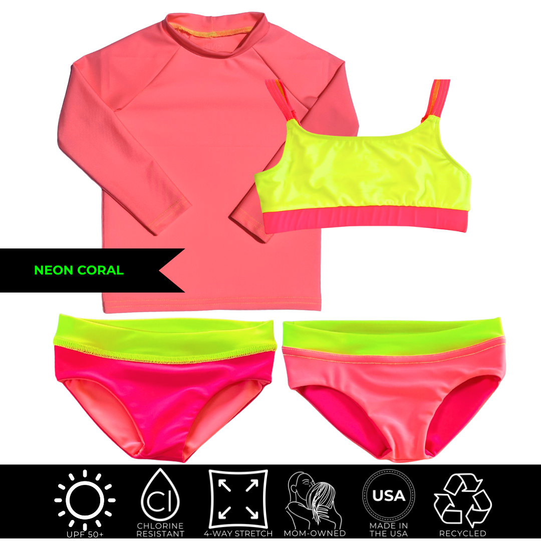 A product lay flat featuring a bright neon coral rash guard and neon pink girls swimsuit set. Neon pink and neon coral reversible bottoms and neon yellow waist band and matching neon yellow neon pink athletic bikini top. The girls neon swimwear set stands out against the background.